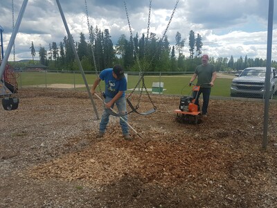 Directors Mike Trithart and Brian Munday work on fluffing up the playground woodchips.